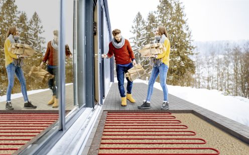 Young lovely couple dressed in colorful sweaters entering their modern home with firewoods in the mountains during the winter